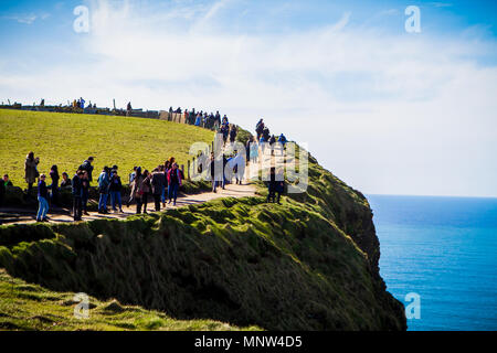 Touristen auf den Klippen von Moher an einem sonnigen Tag in der Grafschaft Clare, Irland Stockfoto