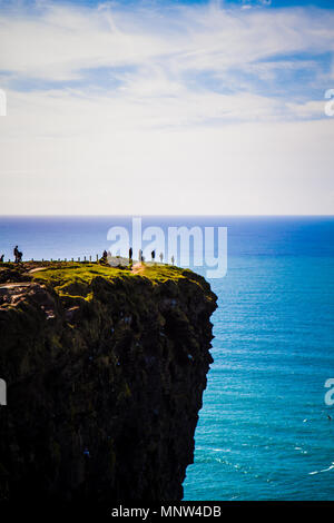 Touristen auf den Klippen von Moher an einem sonnigen Tag in der Grafschaft Clare, Irland Stockfoto