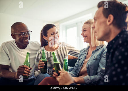 Lachend Gruppe von vielfältigen junge Geschäftsleute trinken Bier beim zusammen Entspannen nach der Arbeit in einem modernen Büro Stockfoto