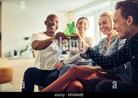 Vielfältige Gruppe junger Geschäftsleute lachen und zusammen Toasten mit Bier während der Feier in einem modernen Büro Stockfoto