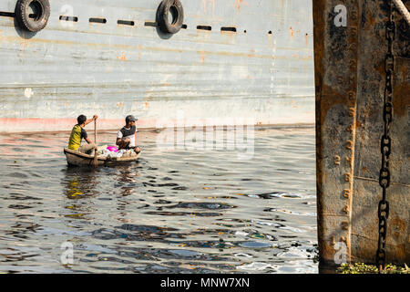 Dhaka, Bangladesh, 24. Februar 2017: Zwei Männer ihre Holz- Bootsfahrt zwischen großen Schiffen auf buriganga Fluss in Dhaka, Bangladesh Stockfoto