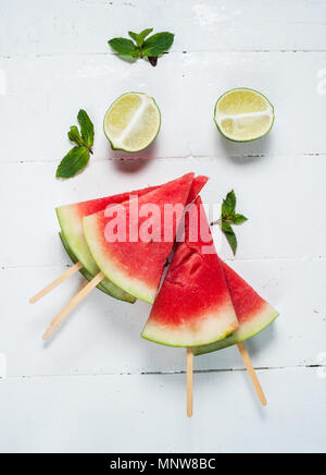 Wassermelone Schicht Eis am Stiel und Kalk auf rustikalem Holz Hintergrund. Stockfoto