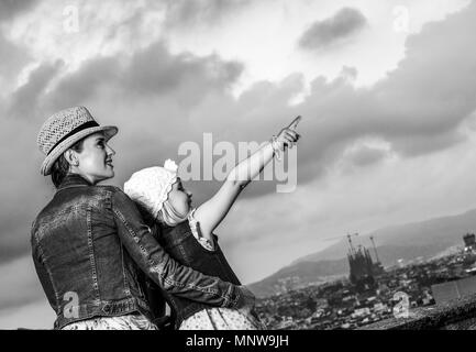 Perfekter Abend mit atemberaubenden Blick. Happy Elegant Mutter und Tochter Reisenden vor Ort Panorama von Barcelona, Spanien zeigt auf etwas Stockfoto