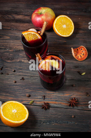Heißer Glühwein mit Gewürzen, Apfel und Orange auf Holz. Stockfoto