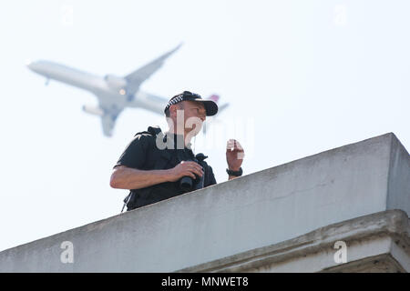 Windsor, Großbritannien. 19 Mai, 2018. Ein Flugzeug vom Flughafen Heathrow fliegen hoch über einen Polizisten auf dem Dach über der High Street beobachten Tausende Gratulanten säumen die Straßen von Windsor die Beförderung Prozession von Prinz Harry und Meghan Markle Zeugnis zu geben, jetzt der Herzog und die Herzogin von Sussex, ihre Hochzeit in St. George's Chapel in Windsor Castle. Credit: Mark Kerrison/Alamy leben Nachrichten Stockfoto