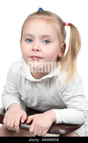 Portrait einer hübschen kleinen Mädchen mit einem Pferdeschwanz seitwärts stützte sich auf einen Stuhl auf weißem Hintergrund Stockfoto