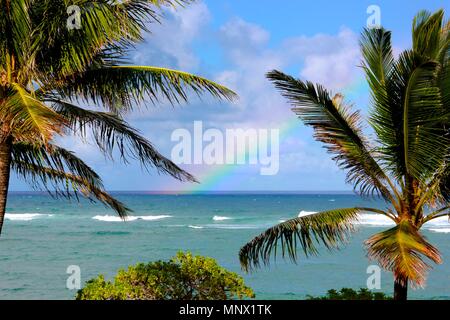 Ein voller Regenbogen begann in den Gewässern an der Ostküste von Kauai, Hawaii und da es immer größer und heller, es bewegte sich in Richtung Küste. Stockfoto