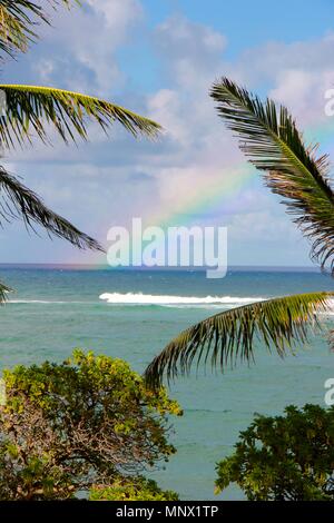 Ein voller Regenbogen begann in den Gewässern an der Ostküste von Kauai, Hawaii und da es immer größer und heller, es bewegte sich in Richtung Küste. Stockfoto