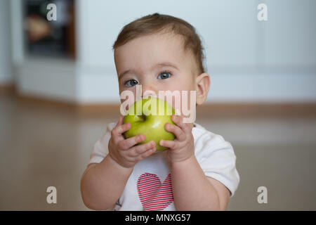 Kleines Kind hält seine Hände apple und nagt Stockfoto