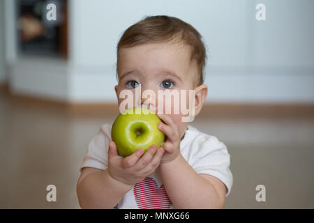 Kleines Kind hält seine Hände apple und nagt Stockfoto