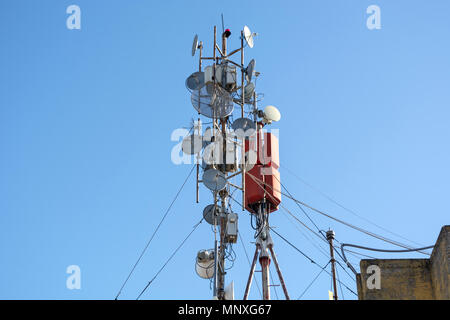 Viele Antennen für das drahtlose Netzwerk, Telekommunikation und Satellitenschüsseln auf dem Dach des Gebäudes. Panel Antennen, Faser, Optik und Netzkabel Stockfoto