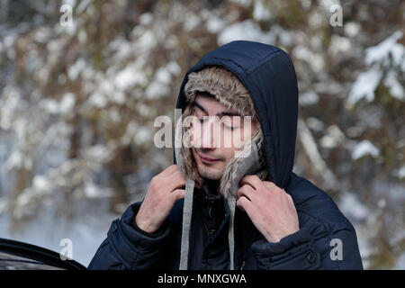 Junger Mann passt seine Kleidung im Winter auf die Straße Stockfoto