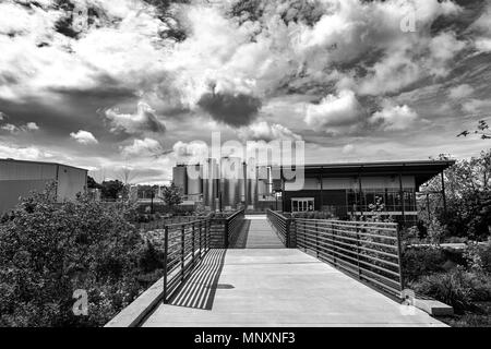 Ein Fußweg führt zum sudhaus an der New Belgium Brewing Company in Asheville, NC, USA, mit dramatischen Wolken über es. Stockfoto