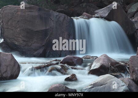 Wasser fallen über große Felsbrocken in einem Rocky Mountain Stream Stockfoto