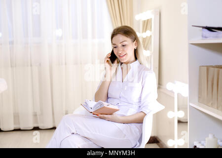 Ziemlich weiblich cosmetologist sprechen von Smartphone am Schaltschrank. Stockfoto