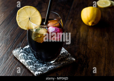 Schwarze Limonade mit Holzkohle, Zitrone und farbenfrohen Bubble ice cubes. Bio Trinken. Stockfoto