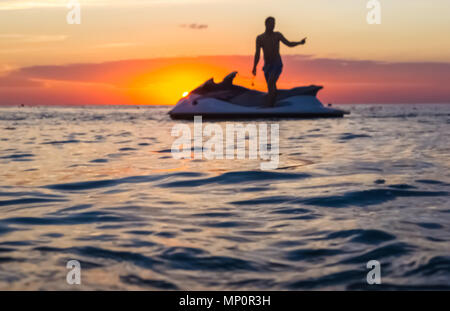 Silhouette eines Mannes auf einem Jet-ski in der Sonne auf dem Meer Sonnenuntergang im Sommer Abend Stockfoto