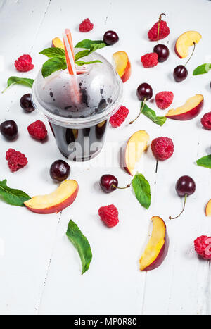 Verschiedene Arten von Früchten mit grünen Blättern und gefrorenen Cocktail Beeren auf weißem Holz Hintergrund. Stockfoto