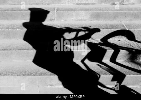 Blurry abstrakte Schatten von einem Radfahrer mit Helm auf und schob sein Rad der öffentlichen Stadt Treppen in Schwarz und Weiß Stockfoto