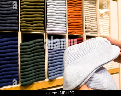 Frauen Hand nehmen das Licht blaue Socke von Socken in den Regalen zum Verkauf in Clothing Store Stapel Stockfoto