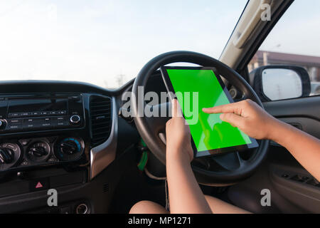 Hand der Frau, die Tablette mit leeren Green Screen Monitor im SUV-Auto Stockfoto