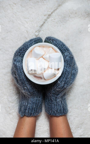 Hände auf gestrickte Handschuhe Holding heiße Schokolade mit Marshmallows. Stockfoto