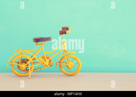 Vintage Metall gelb Fahrrad Spielzeug über Holz- Tabelle Stockfoto