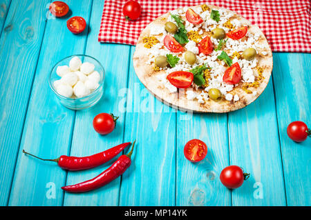 Pita mit Käse, Tomaten, Oliven und Grün auf Blau Holz- Hintergrund Stockfoto