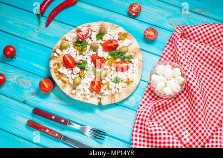 Pita mit Käse, Tomaten, Oliven und Grün auf Blau Holz- Hintergrund Stockfoto