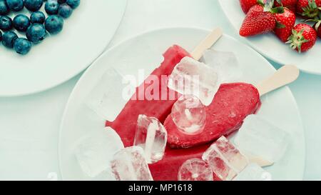 Lecker lecker lecker Hand aus Eis mit Früchten mit Erdbeere Heidelbeere und Eis, flatlay Nahaufnahme Stockfoto