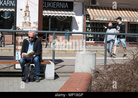 Poznan, Polen, 30. April 2018: älterer Mann eine Zeitung lesen sitzen auf einer Bank in der Nähe des Marktes Stockfoto