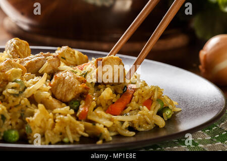 Gebratener Reis Nasi Goreng mit Huhn und Gemüse auf einem Teller. Indonesische Küche. Stockfoto