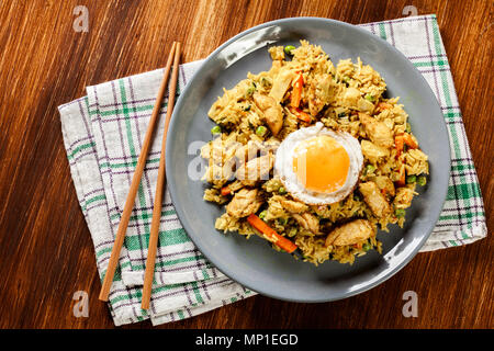 Gebratener Reis Nasi Goreng mit Huhn Eier und Gemüse auf einem Teller. Indonesische Küche. Ansicht von oben Stockfoto