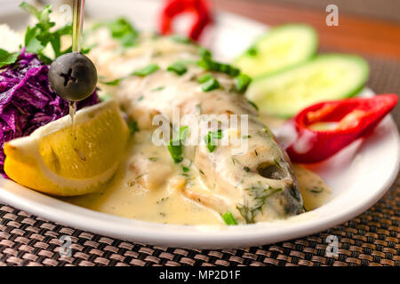 Frische und köstliche Forellen in weiße Rahmsauce mit Gemüse auf einem weißen Teller. Close-up. Stockfoto
