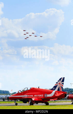 Das Red Arrows Aerobatic zeigt das Team BAE Hawk Jet auf der Rollbahn, während der Rest des Teams über uns fliegt. RAF Waddington, Lincolnshire, England Stockfoto