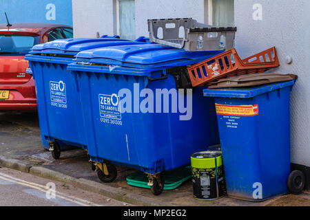 Reihe der großen blauen kommerzielle Verwertung der Behälter in einer Nebenstraße hinter einem gewerblichen Räumen. Teignmouth, Devon. Feb 2018. Stockfoto