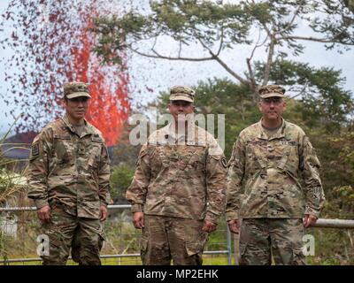 Der Oregon National Guard Joint Task Force 5-0 Team, Oberst Neal Mitsuyoshi, Brig. Gen. Kenneth Hara und Oberst David Williamson posieren vor einem massiven Lavafontäne aus Spalte 17 durch den Ausbruch des Kilauea Vulkans am 18. Mai 2018 in Pahoa, Hawaii verursacht zu spucken. Stockfoto