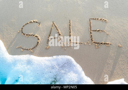 Wort Verkauf handschriftlich in Sand von tropischen Strand mit weichem Blue Ocean Wave für den Hintergrund. Sommer Vertriebskonzept. Stockfoto