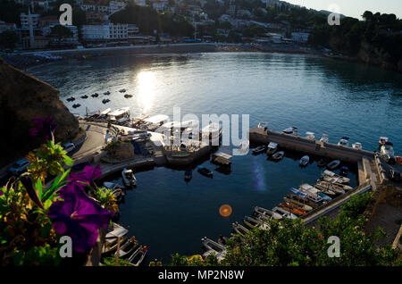 Kleine Fischerboote Marina mit runden Pier. Wide Angle Shot mit einer Stadt und Strand Mala Plaza für den Hintergrund. Ulcinj, Montenegro. Stockfoto