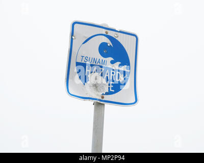 Vandalized Tsunami Hazard Zone Schild in der Nähe der Küste Stockfoto