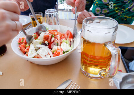 Eine Platte mit horiatiki Salata (Griechischer Salat) mit einem Krug mit Bier in einer traditionellen griechischen Taverne Stockfoto