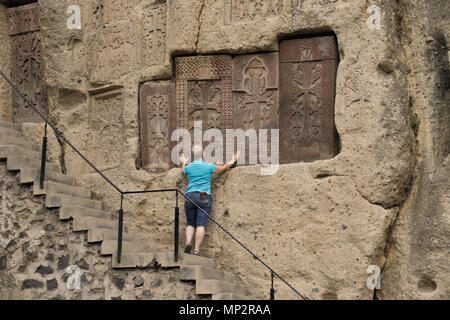 Eine Frau Studien kunstvoll geschnitzten Stein khatchkars im Rock bei Geghard Kloster (Kloster der Speer), Garni, Armenien embedded Stockfoto