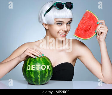 Glückliches Mädchen mit Reife Wassermelone. Foto der lächelnde Mädchen in Sonnenbrille auf blauem Hintergrund. Detox Konzept Stockfoto