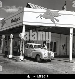 1950 s, historischen, einen männlichen Begleiter an einem Mobilgas Service Station der Frontscheibe eines Kfz, London, England, UK reinigt. Stockfoto
