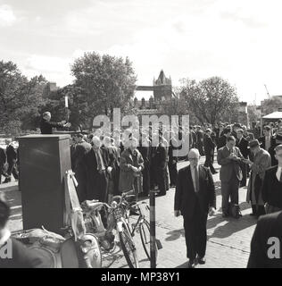 1950er Jahre, die Tower Bridge, London, mittags ein Masse von männlichen Stadt Arbeiter sammelt ein Mann auf seinem soapbox eine Rede an einem öffentlichen Ort zu hören. Stockfoto