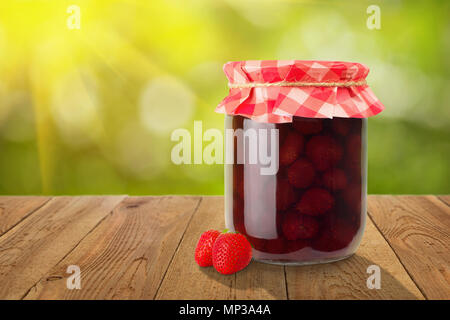 Erdbeermarmelade in Glas Glas mit Papier und frische Beeren auf hölzernen Tisch gedeckt. Konzept der Sommer hausgemachte haltbar gemacht Früchte Stockfoto