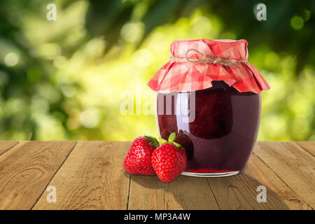Erdbeermarmelade in Glas Glas mit Papier und frische Beeren auf hölzernen Tisch gedeckt. Konzept der Sommer hausgemachte haltbar gemacht Früchte Stockfoto