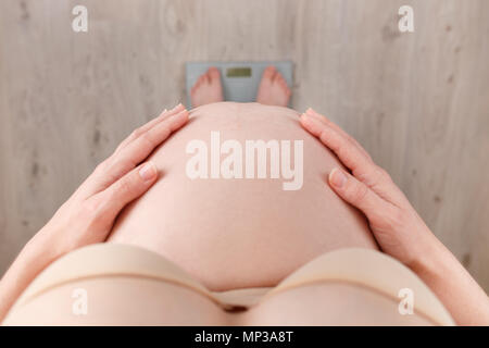 Closeup schwangere Frau auf Skalen, die Ansicht von oben. Kontrolle der Gewichtszunahme in der Schwangerschaft Zeit Stockfoto