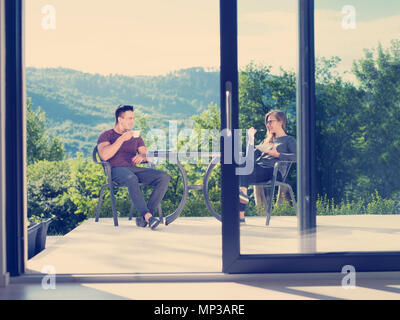junge schöne hübsches Paar Morgenkaffee und Frühstück vor der ihre Heimat Luxusvilla Stockfoto
