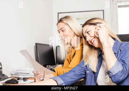 Zwei weibliche Kollegen nebeneinander sitzen und Diskutieren über Schreibarbeit. Stockfoto